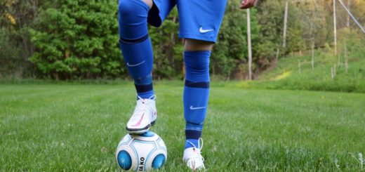 person in blue pants and blue socks standing on green grass field